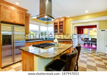 Yellow kitchen interior. View of island with built-in stove and kitchen hood above it.