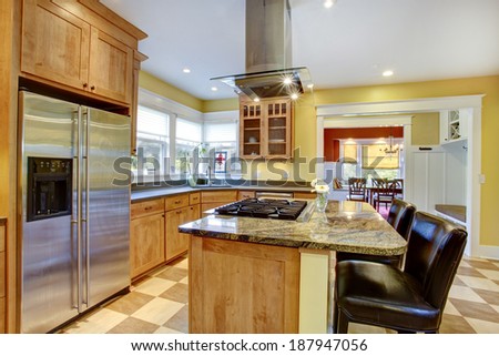 Yellow kitchen interior. View of island with built-in stove and kitchen hood above it