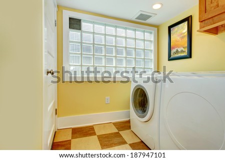 Yellow laundry room with washer, dryer and glass block window