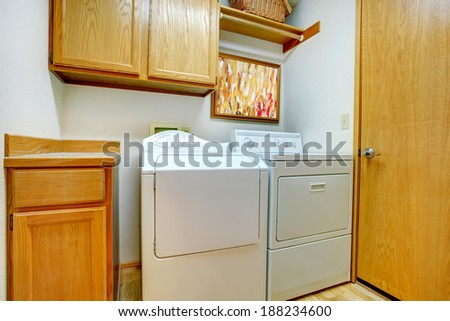 Small laundry room with wooden cabinets, and white appliances
