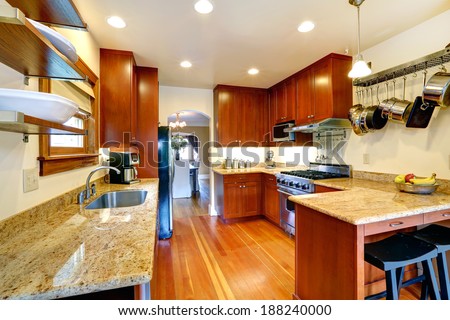 Practical kitchen room interior. Cabinets, steel appliances, hanging pot rack. Kitchen room has a dining area