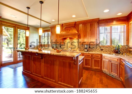 Spacious kitchen room with honey cabinets, back splash trim and kitchen island. Room has door to the backyard deck