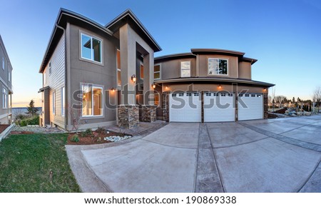 Luxury house exterior with  three car garage and driveway. Evening view