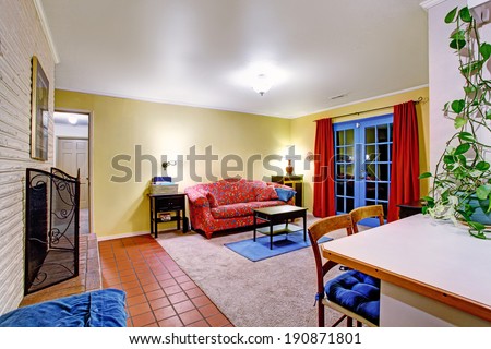 Bright contrast colors living room with red sofa, small black coffee table, blue french door with red curtains