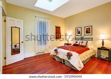 Ivory bedroom with old hardwood floor. View of bed with beautiful bedding