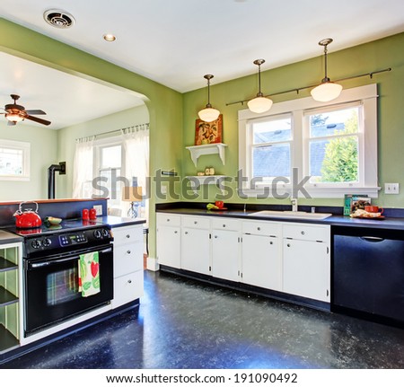 Kitchen room with green walls, white cabinets and black appliances
