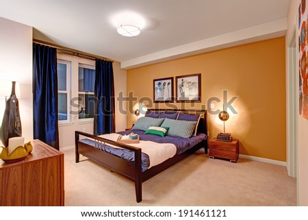Elegant bedroom with black wooden bed covered in purple bedding
