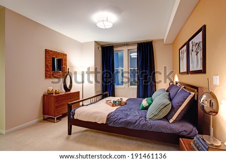 Elegant bedroom with black wooden bed covered in purple bedding