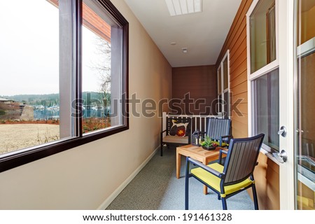 Narrow screened porch with wooden table and chairs