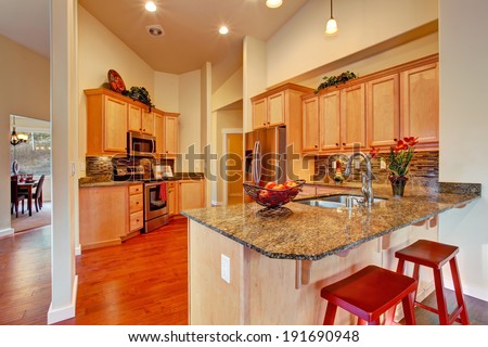 Soft colors modern kitchen area with wooden storage cabinets, steel appliances and tile back splash trim