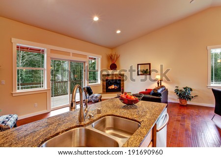 House with high vaulted ceiling. View of living room with fireplace and walkout deck from kitchen area