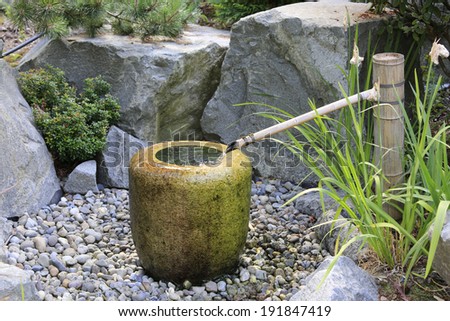Japanese style pump fountain . Water running from a bamboo tube into a stone vase