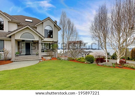 Luxury house exterior with flower beds and lawn. Water view