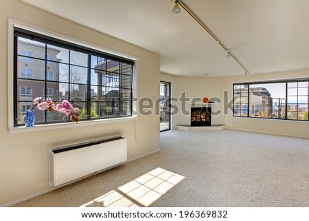 Bright empty room with fireplace and walkout deck. View of window with flower.