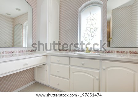 White wooden vanity in pink bathroom  with arch window