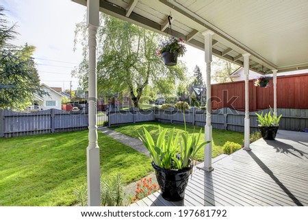 Entrance column porch with flower pots. View of fenced front yard with walkway
