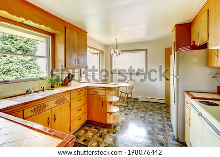 Kitchen room with honey rustic storage cabinets, shiny linoleum floor and small dining area