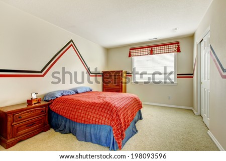 Ivory bedroom with painted walls, wooden nightstand and dresser. VIew of bed in bright blue and right colors