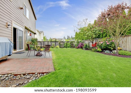 Big house with walkout small deck. View of lawn and flower bed