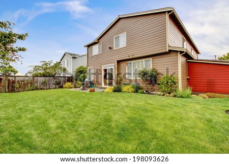 Big house with walkout small deck. View of lawn and flower bed