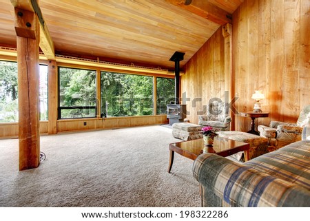 Spacious log cabin living room with high vaulted ceiling and carpet floor.  View of antique stove and furniture set