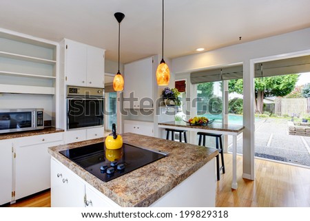 Kitchen room with white appliances, kitchen island and walkout deck to backyard