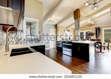Modern kitchen with dark brown cabinets, steel appliances and kitchen island with bar stools