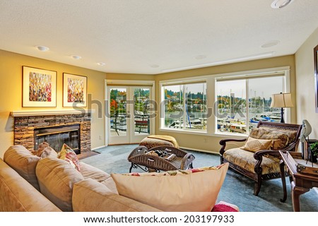 Living room with walkout deck and water front view. Furnished with antique sofa and chair. Gig Harbor.