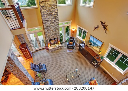 Luxury living room with high ceiling, brick columns and fireplace. View from upstairs deck