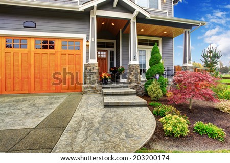 Luxury house entrance porch with stone column trim. View of  walkway with landscape
