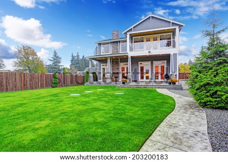 Luxury house with backyard walkout deck and column porch. View of lawn and concrete walkways