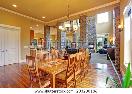 Luxury house with high ceiling and brick columns. View of dining room with long table