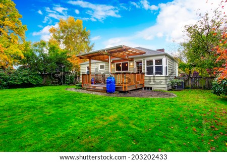 Small house with backyard walkout deck. View of lawn and trees during fall time