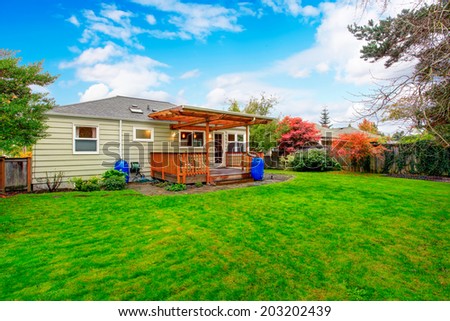 Small house with backyard walkout deck. View of lawn and trees during fall time