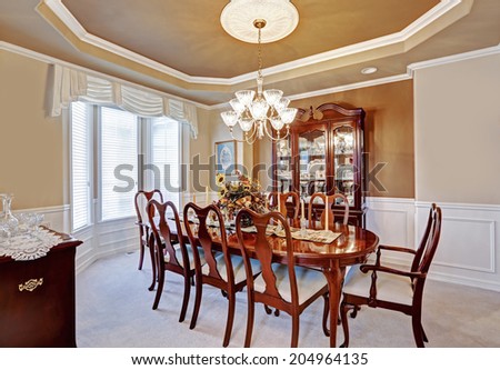 Beautiful dining room interior in luxury house. Wooden dining table set blend perfectly with  light brown walls and white trim