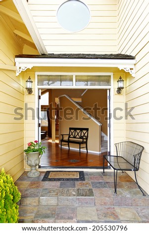 Spacious entrance hall with high ceiling and small wooden bench. View from entrance porch