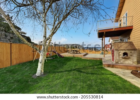 View of backyard with wooden walkout deck with patio area and kids playground