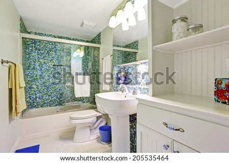Refreshing white bathroom with aqua tile wall trim, white wooden cabinet, washbasin stand and toilet