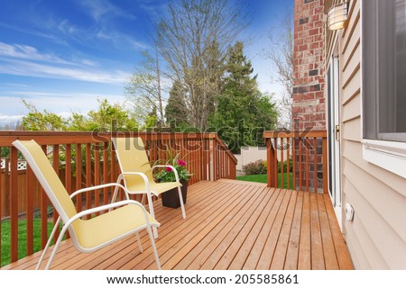 Small wooden walkout deck with two yellow chairs and flower pot