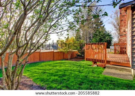 Small fenced backyard with wooden walkout deck