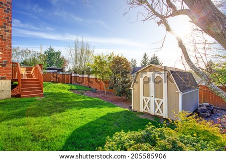 Fenced backyard with wooden walkout deck and small shed