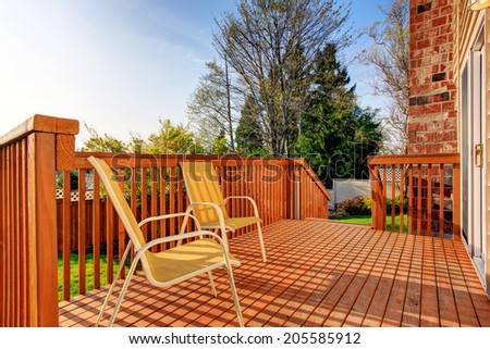 Small wooden walkout deck with two yellow chairs