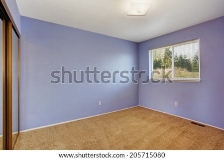Small empty bright room in lavender color with one window and soft brown carpet floor