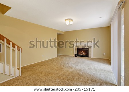 Empty house interior. View of empty living room with fireplace and soft carpet floor