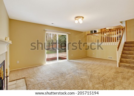 Empty house interior. View of empty living room with walkout deck and staircase to kitchen