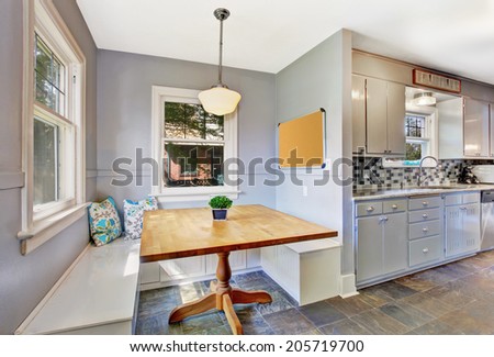 Kitchen room interior with bright dining area. View of wooden table and white benches