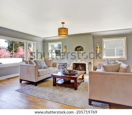 Light grey living rom with hardwood floor and rug. Furnished with white sofas and wooden coffee table