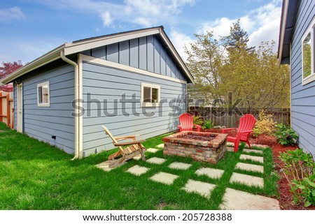 Small backyard with shed and patio area. View of brick fire pit and deck chairs