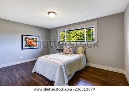 Light blue bedroom with dark brown hardwood floor. Furnished with single bed in white bedding