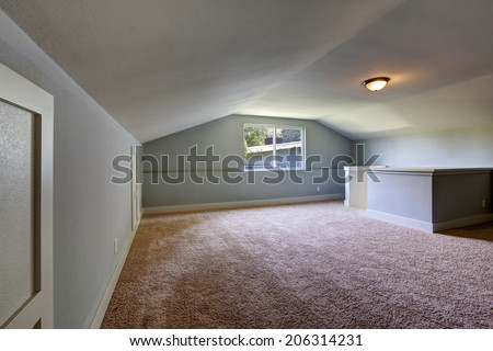 Empty room with brown carpet floor, light blue walls and low vaulted ceiling